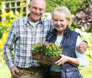 Assisted Living residents holding wooden box full of flowers in garden